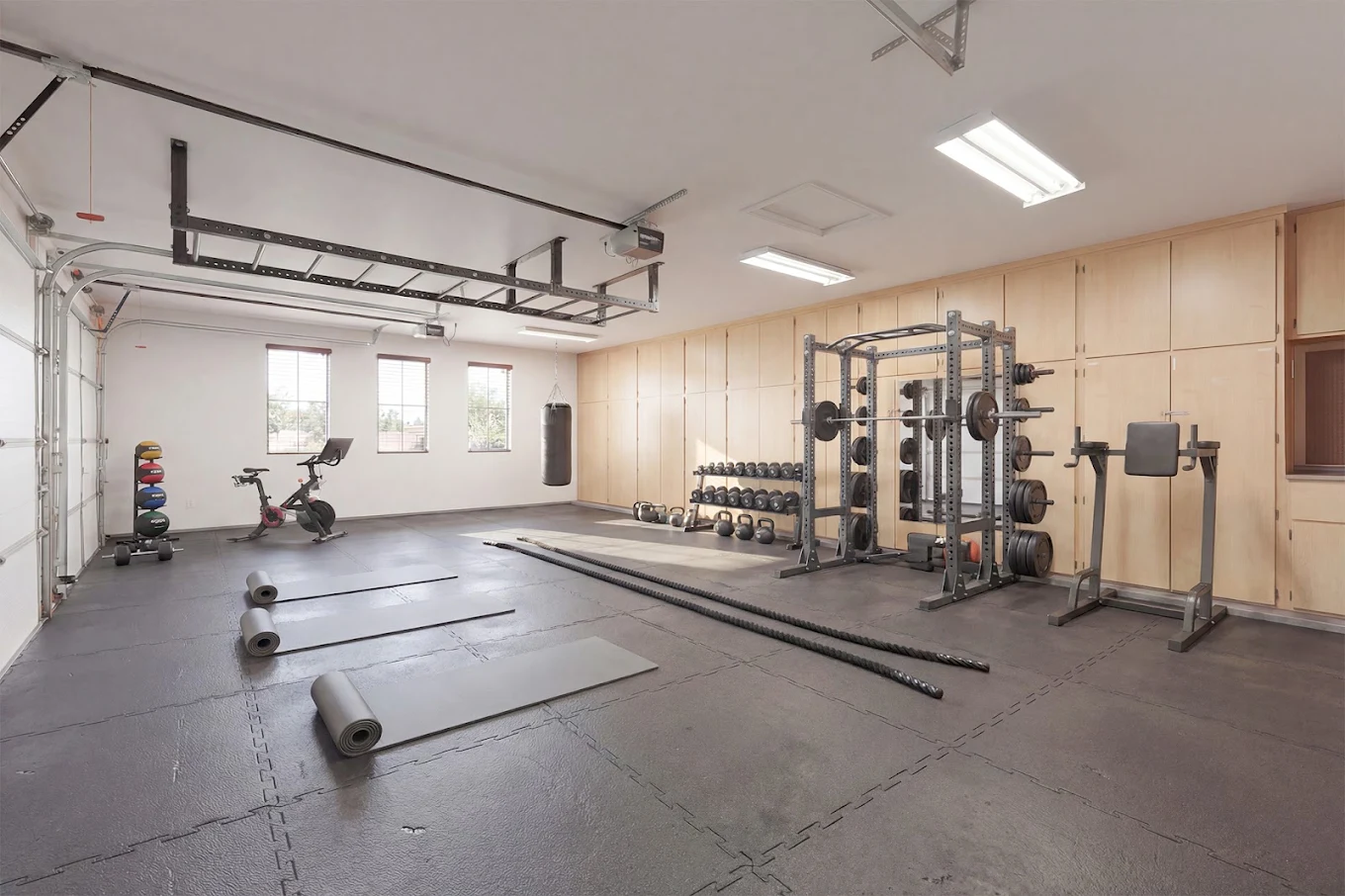 Fitness room with weight rack, dumbbells, exercise bike, mats, and battle ropes