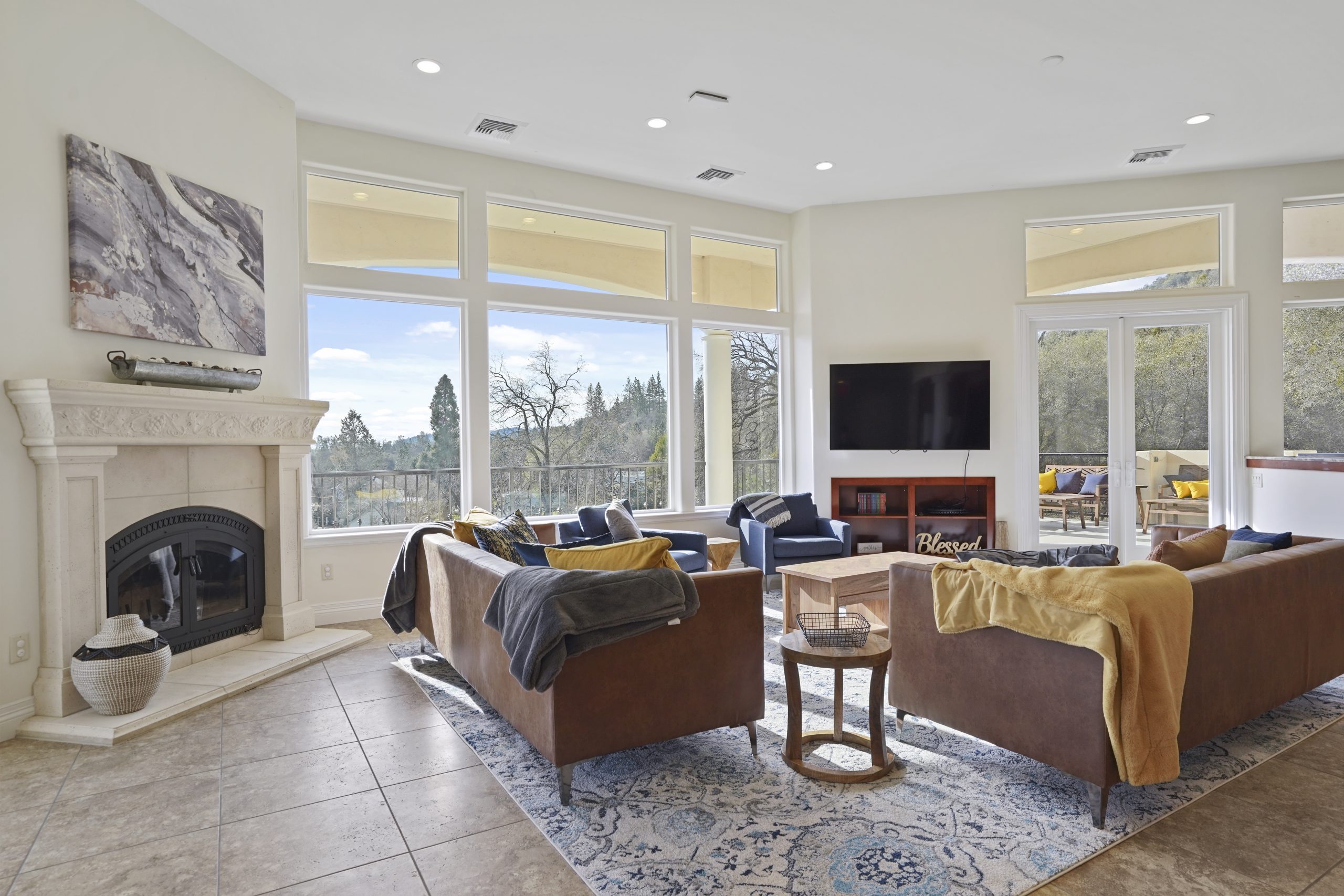 Bright living room with large windows, sofas, and a fireplace.