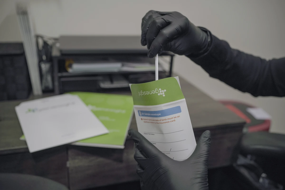 Gloved hand holding GeneSight testing kit