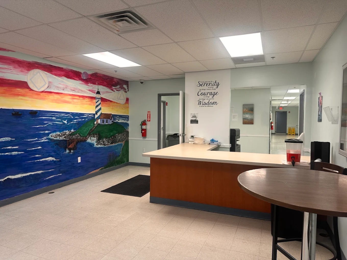 Front desk beside a colorful lighthouse and ocean mural
