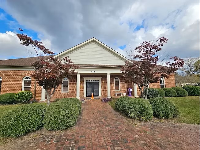 Red brick clinic with white columns and trimmed shrubs