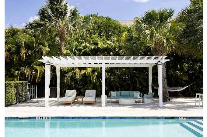 Poolside lounge chairs and canopy with palm trees