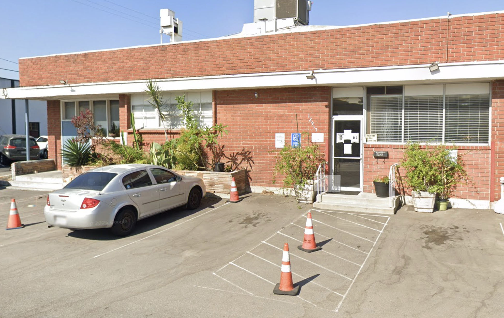 Single-story red brick building with parking and a glass entrance