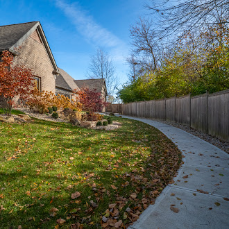 Paved path beside building with fall trees.