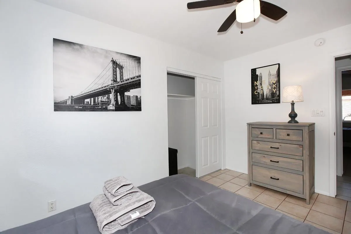 Furnished bedroom with bed, dresser, closet and fresh towels at the Phoenix sober living residence