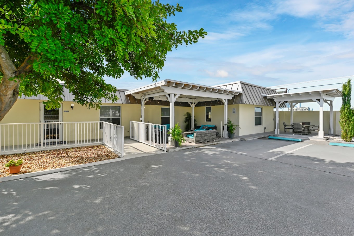 Front entrance with covered seating area and white railings.
