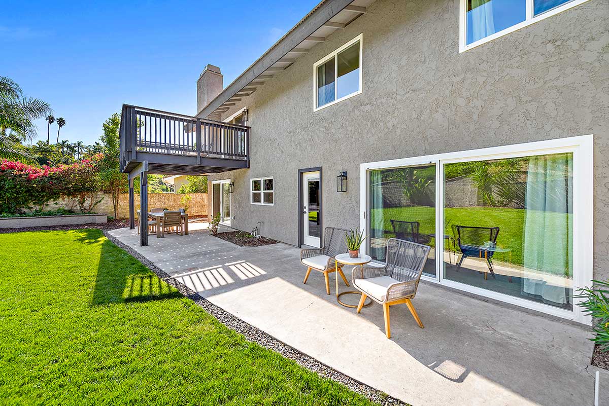 Landscaped backyard with patio seating and upper deck