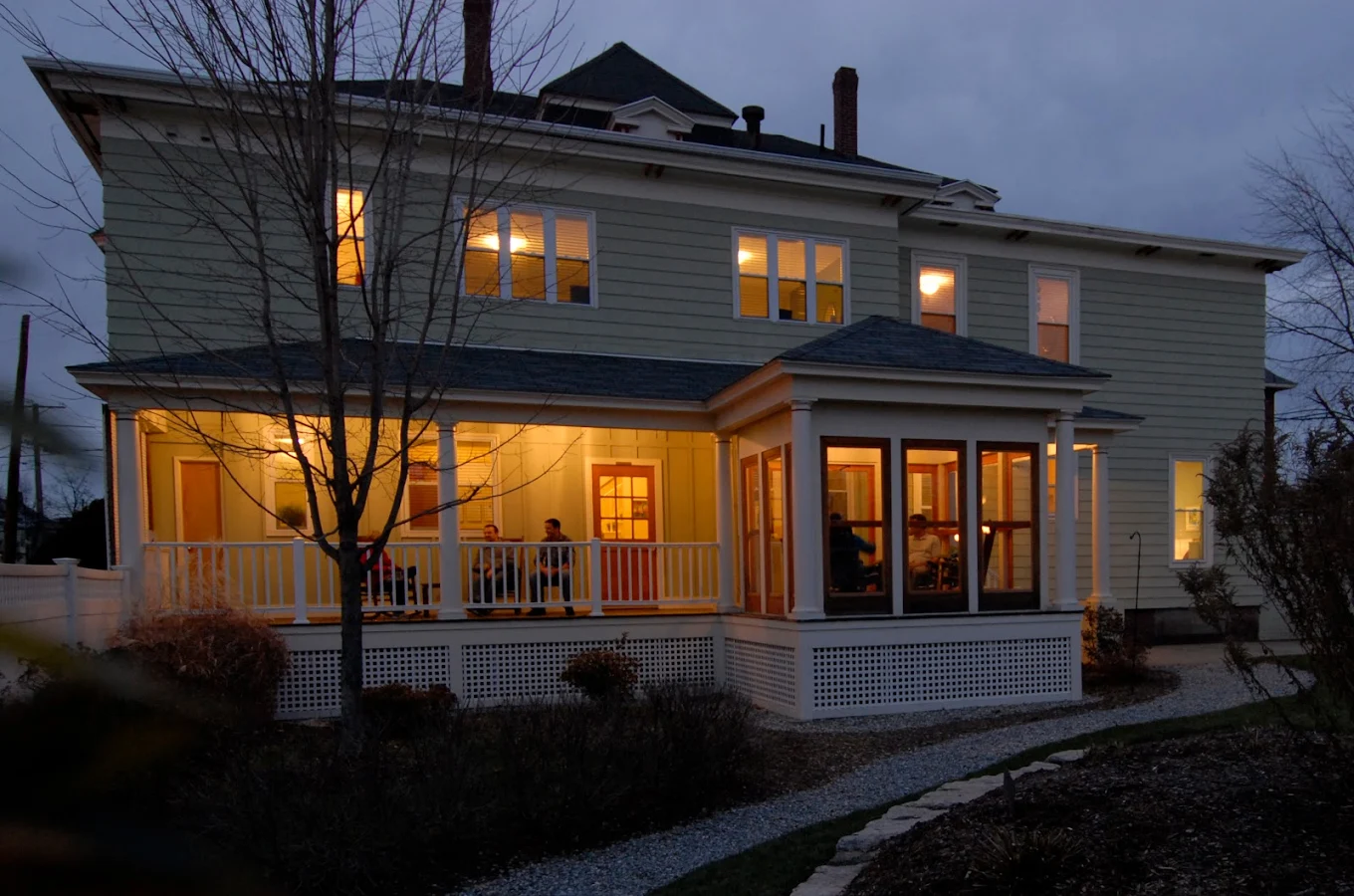 Large residential home with lit porch at dusk