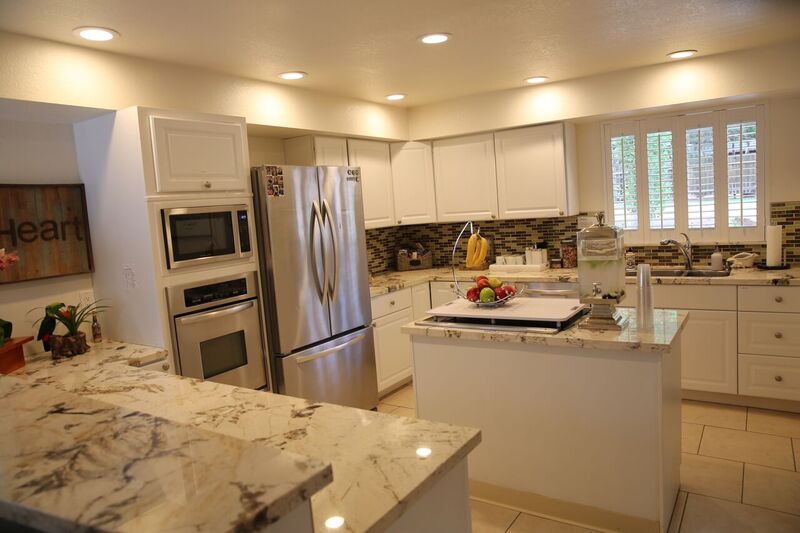 Spacious kitchen with white cabinets and marble countertops