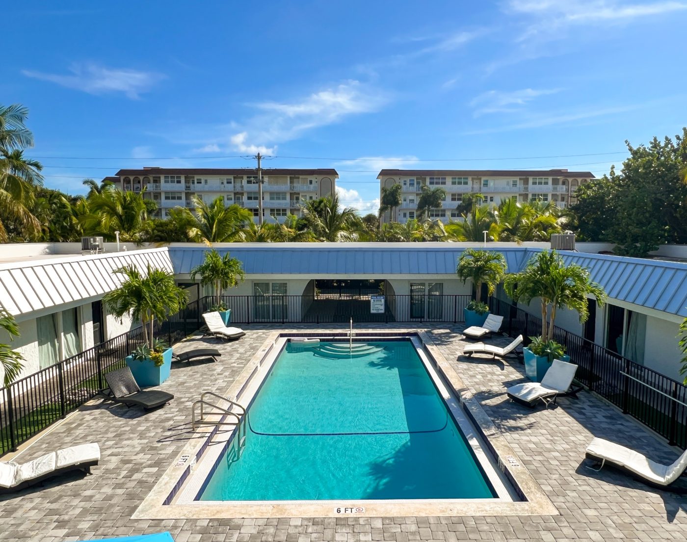 Elevated view of outdoor pool courtyard surrounded by palm trees and lodging buildings