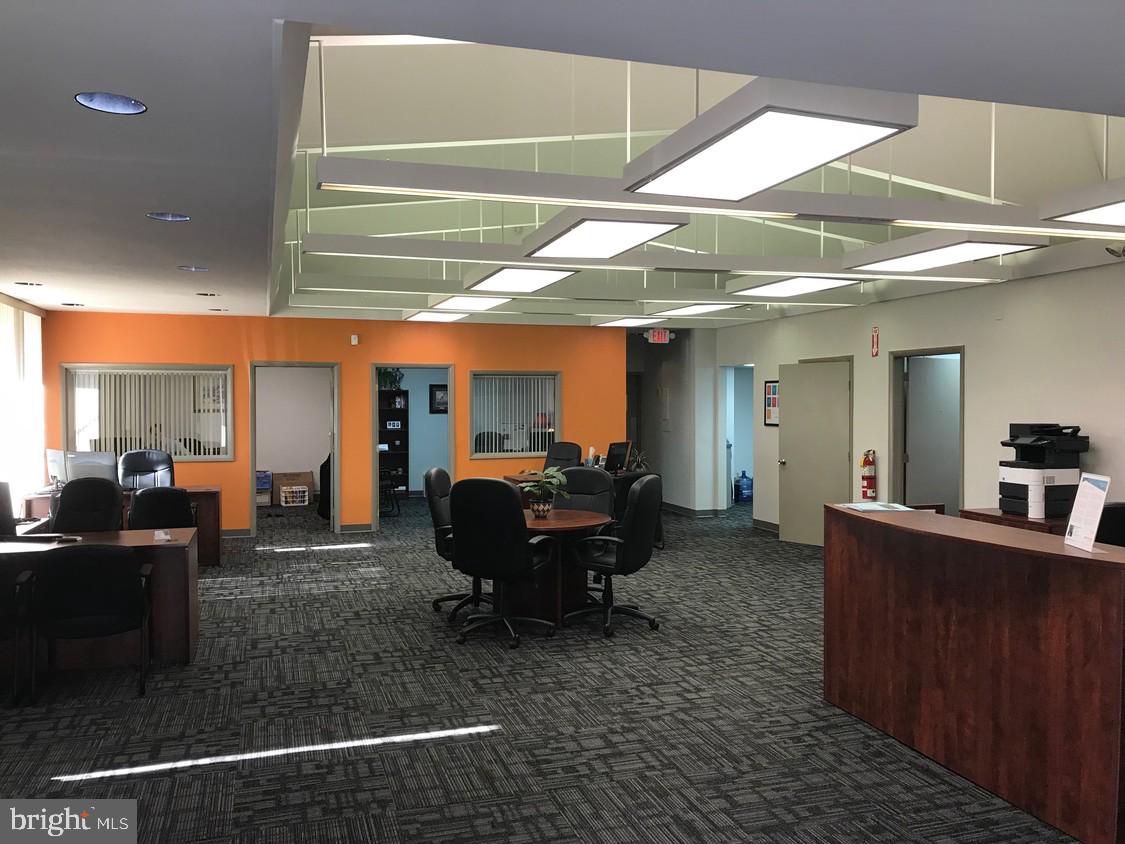 A spacious and bright office area with modern lighting and multiple seating options for visitors.