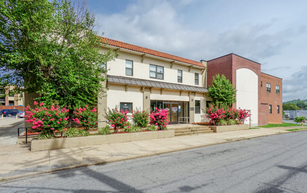 Exterior front view of CADAS main building with red flowers