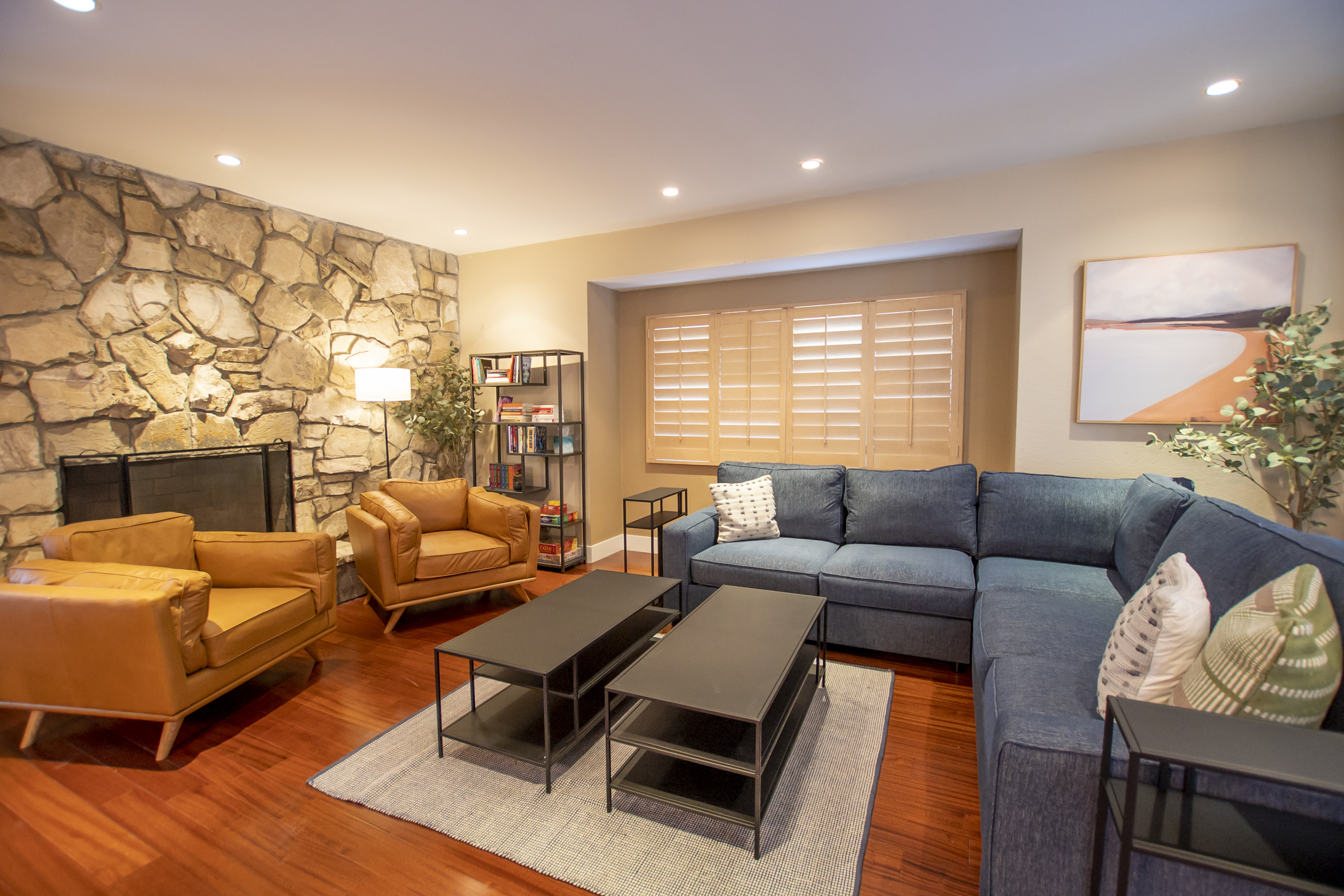 Living room with a stone fireplace, blue sectional, and leather chairs