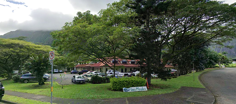 Building surrounded by trees with parking area in front