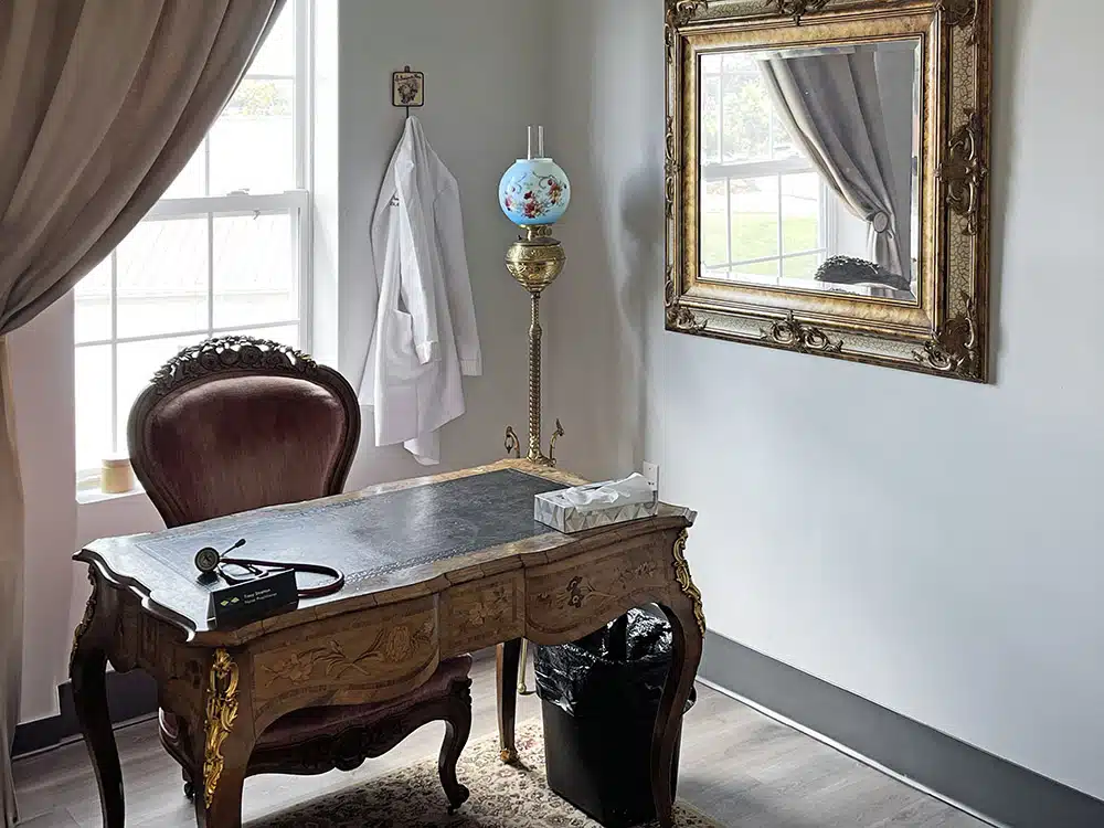 Small office with desk, chair, and medical coat on wall