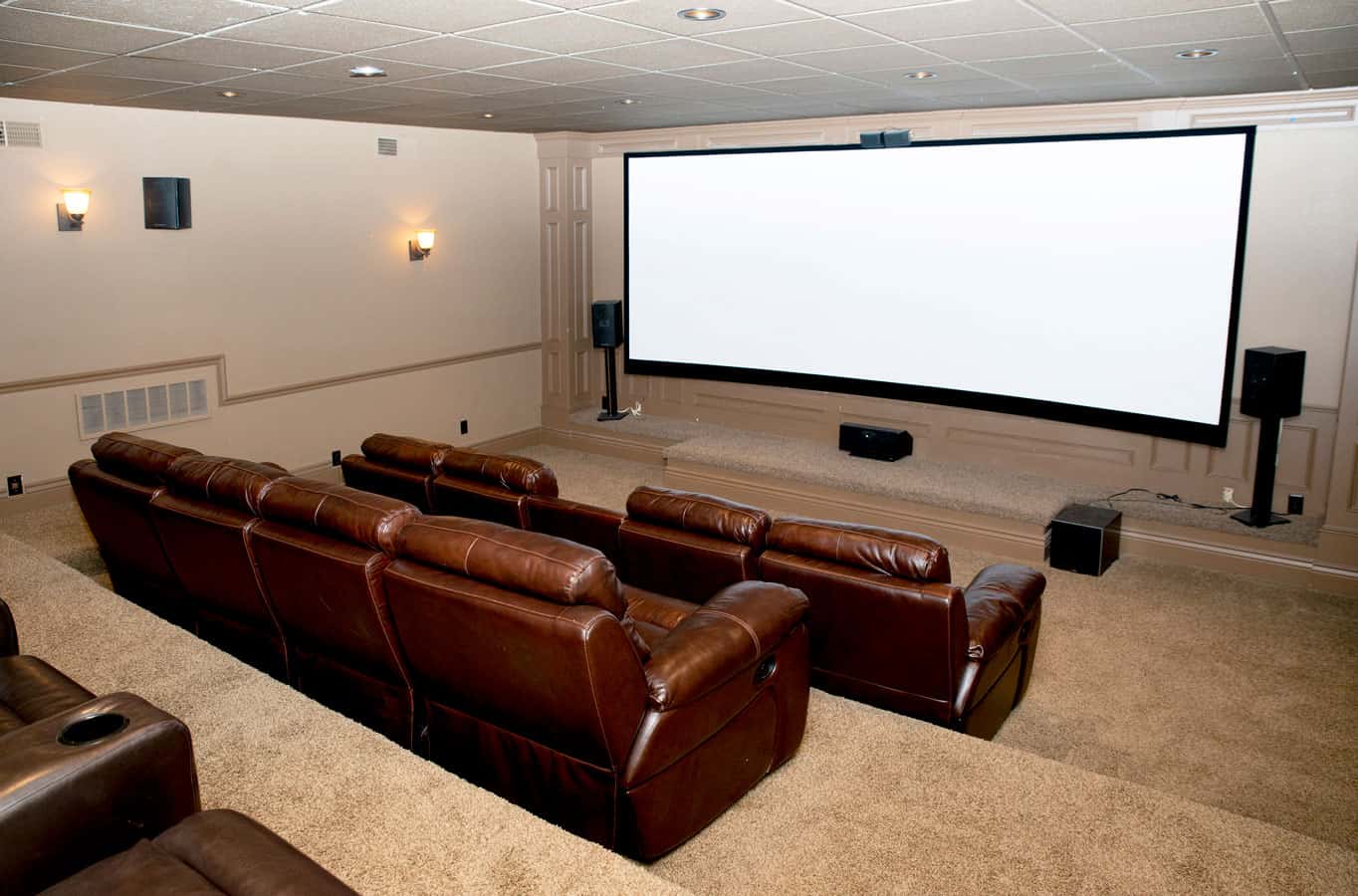 Home theater with leather recliners facing a large screen.