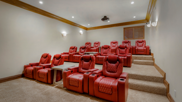 Private home theater with tiered red recliner seating and carpeted floors
