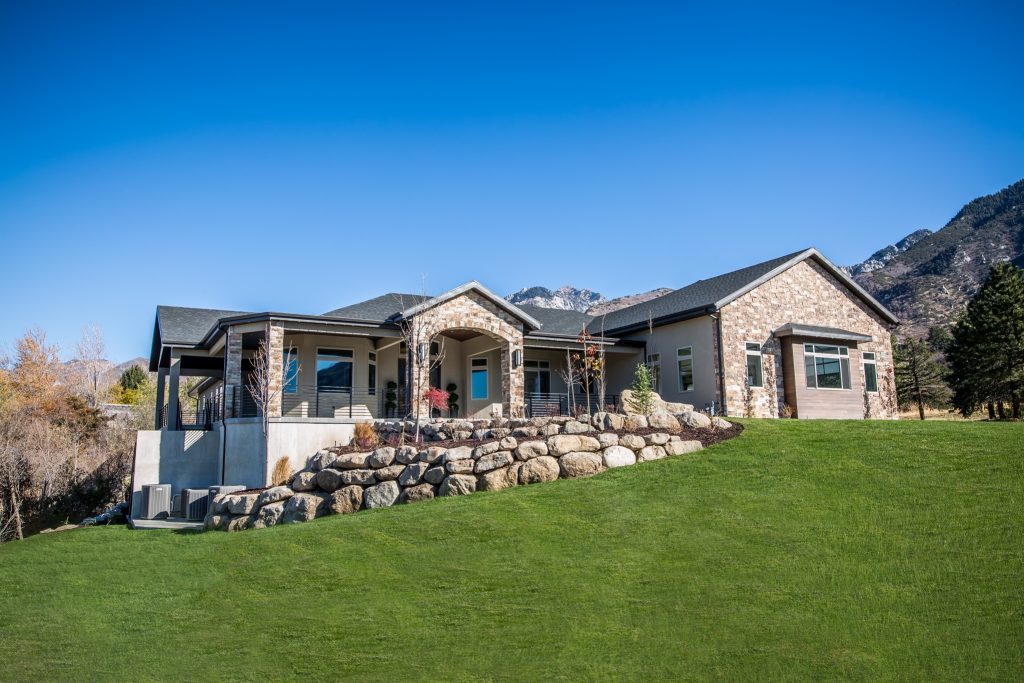 Stone-accented facility on a lawn beneath mountain peaks