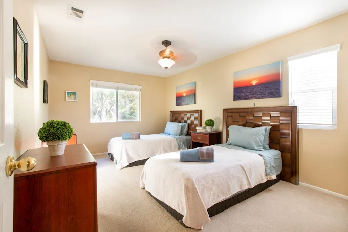 Bright shared bedroom with twin beds and sunset artwork