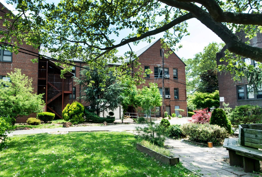 Brick rehab building with garden and trees in sunny courtyard