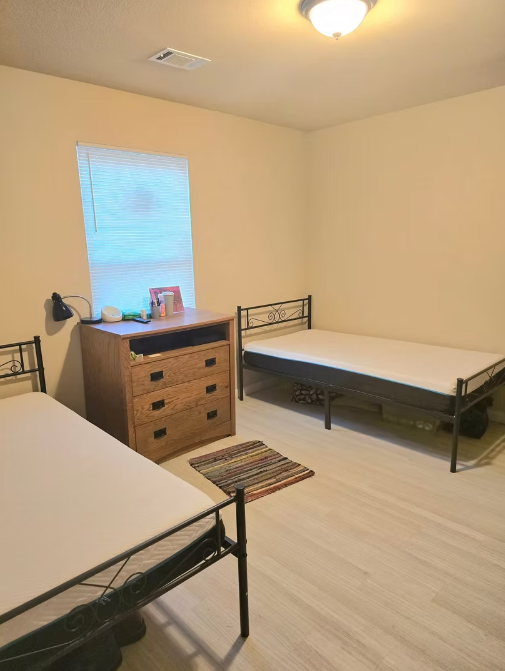 Simple shared bedroom with two twin beds and wooden dresser