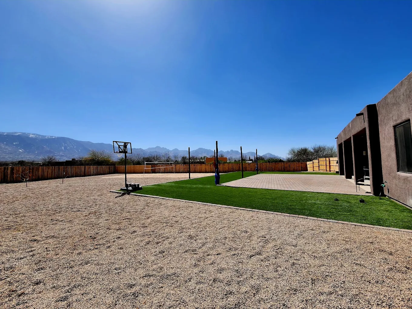 Outdoor recreation area with basketball hoop, artificial turf, volleyball net, and mountain views