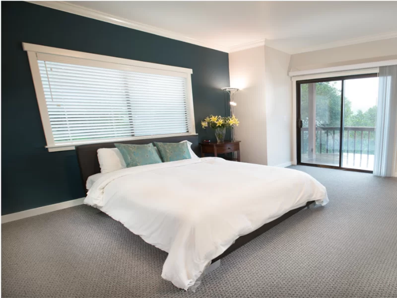 Modern bedroom with large bed, natural light, and balcony access
