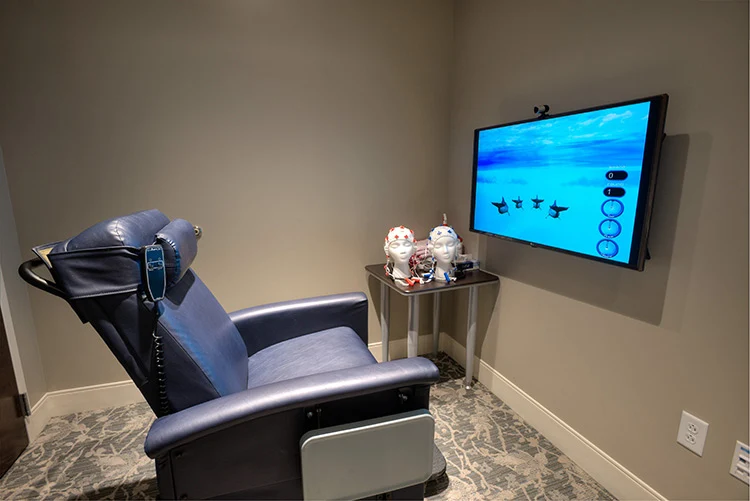 Treatment room with a reclining chair, wall-mounted interactive screen, and medical monitoring equipment