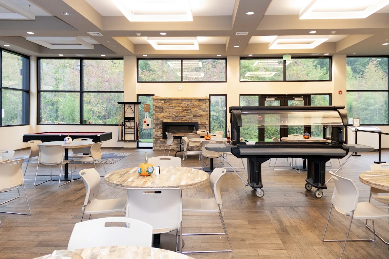 Bright common area with tables, pool table, and fireplace