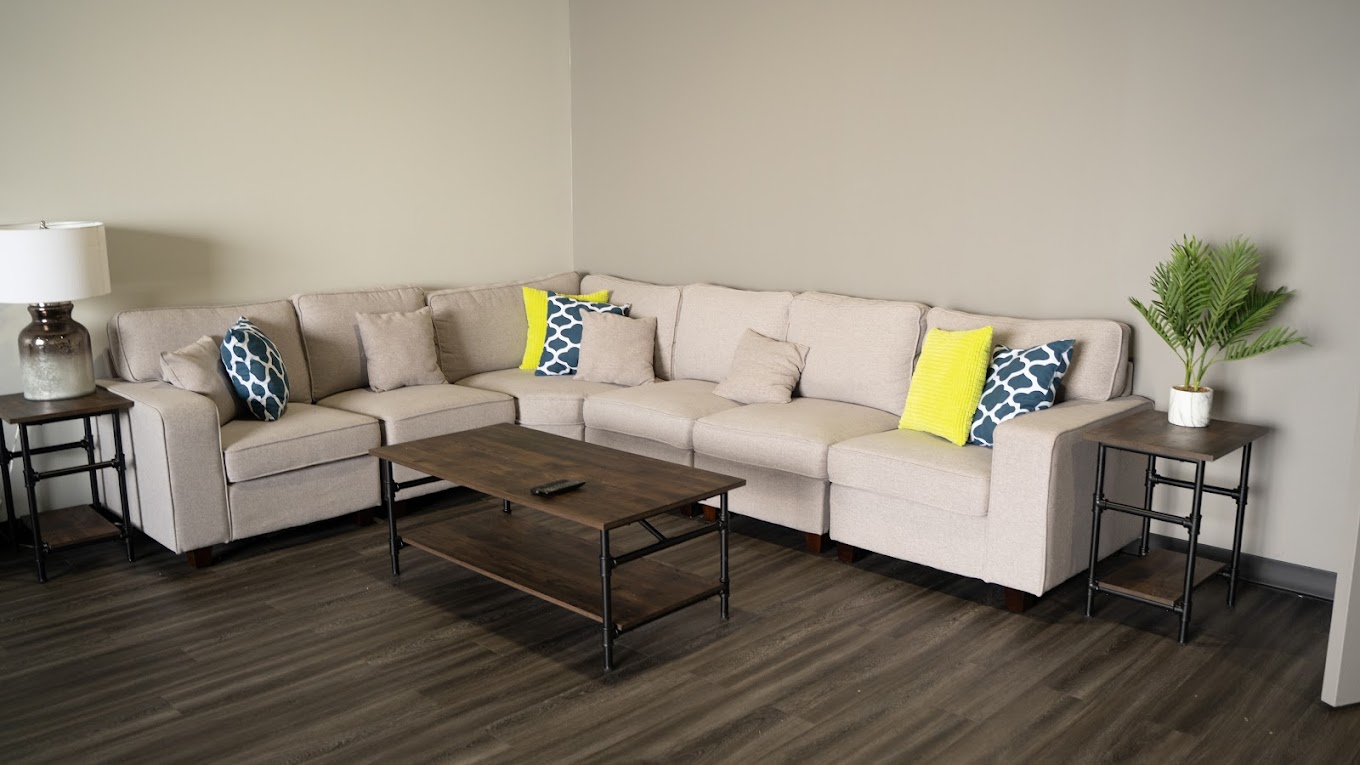  lounge area with a beige couch, wooden tables, and a modern design.
