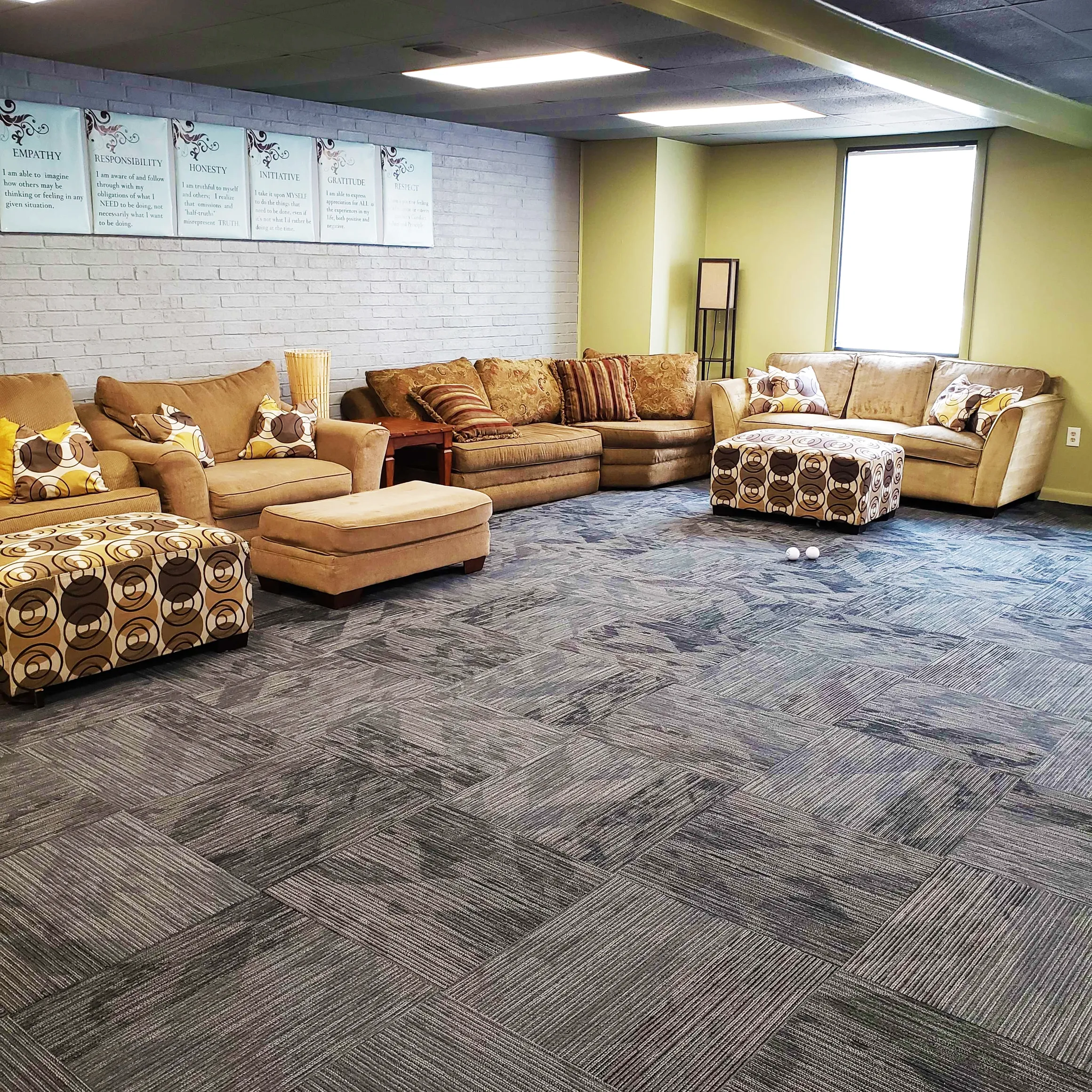 Comfortable group therapy room with sofas and patterned ottomans
