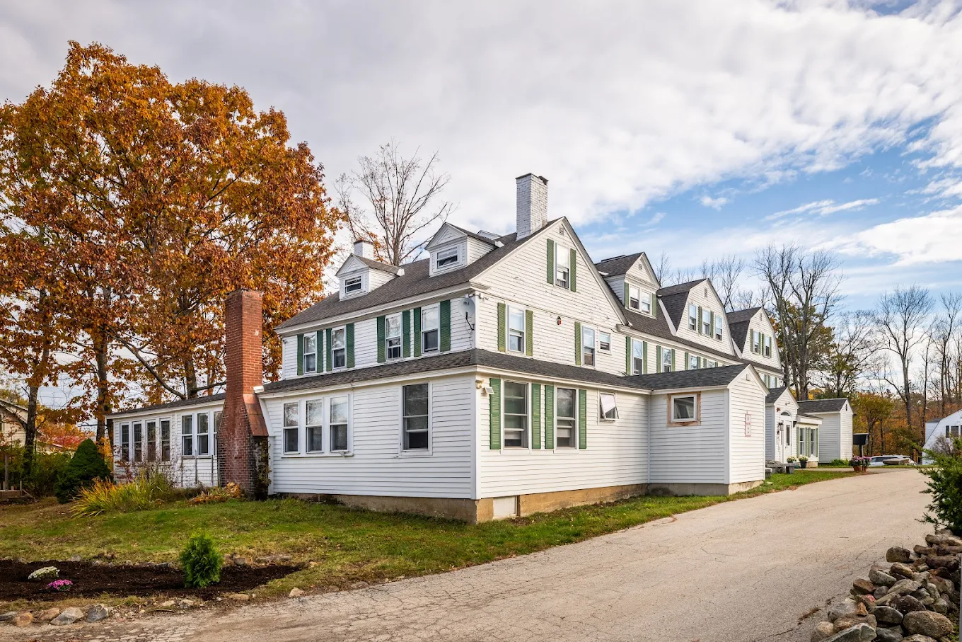  White house with green shutters and a brick chimney
