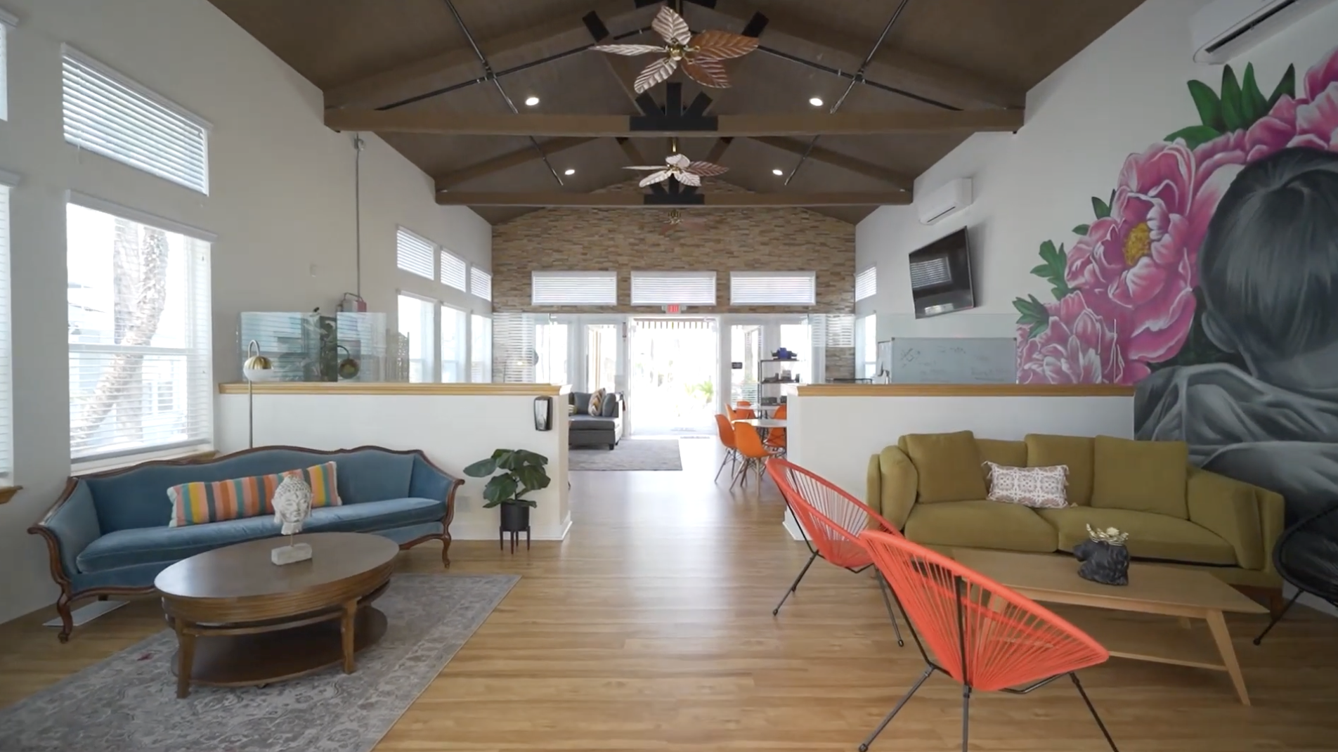 Bright lounge with mural, sofas, and vaulted ceiling fans