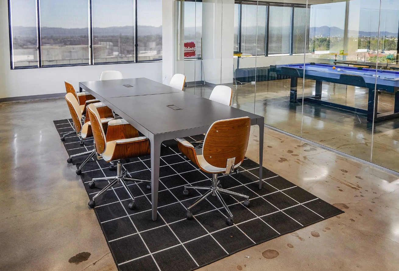 Modern meeting room with conference table, glass walls, and city views