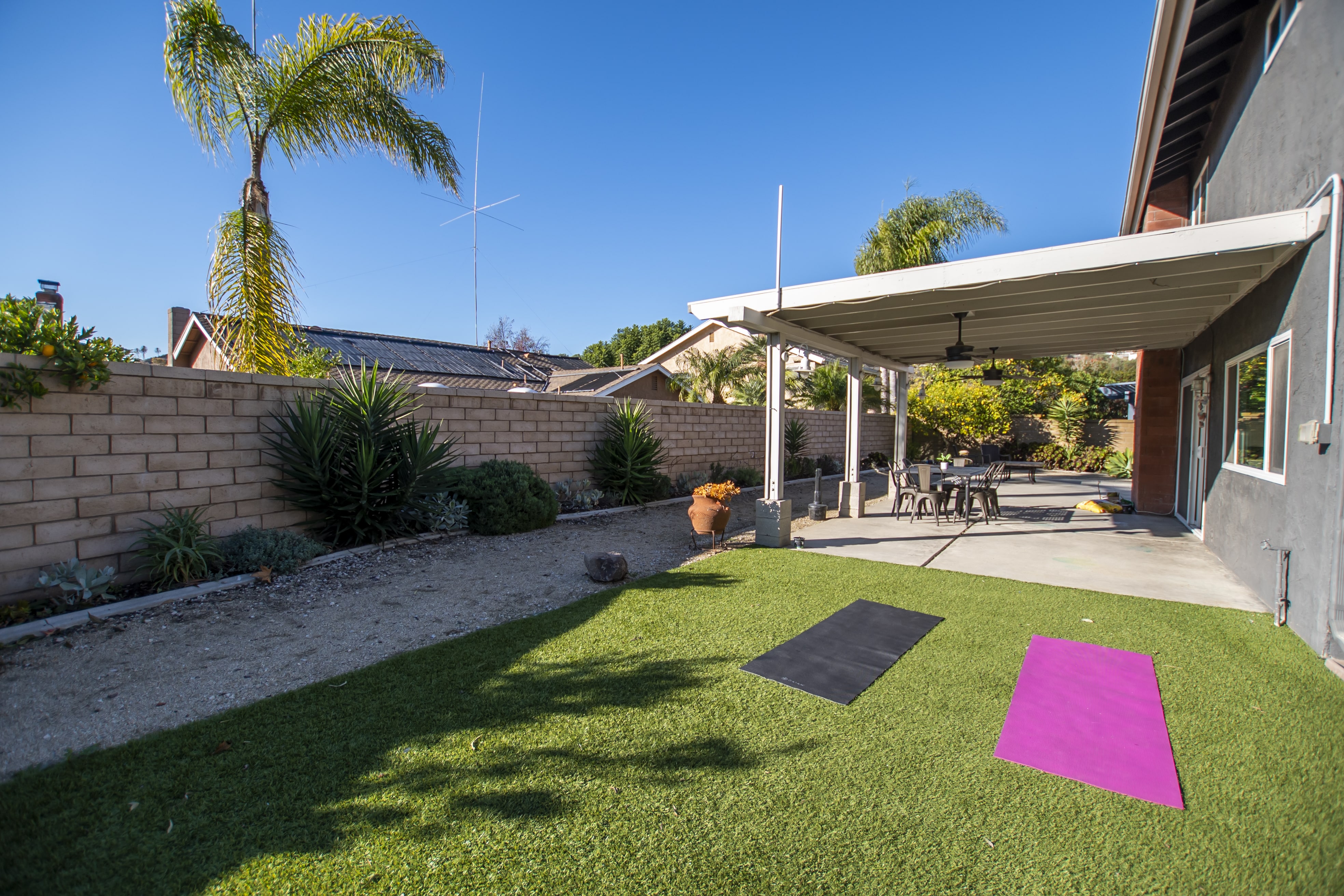 Two yoga mats on turf in a private backyard