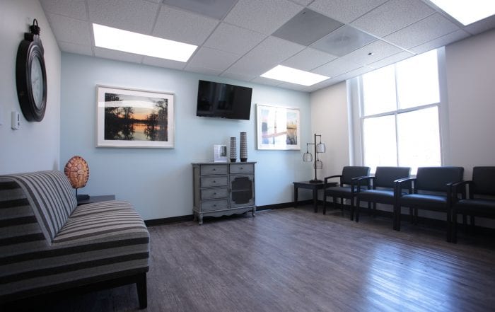 Lounge with wall-mounted TV, chairs, and natural light
