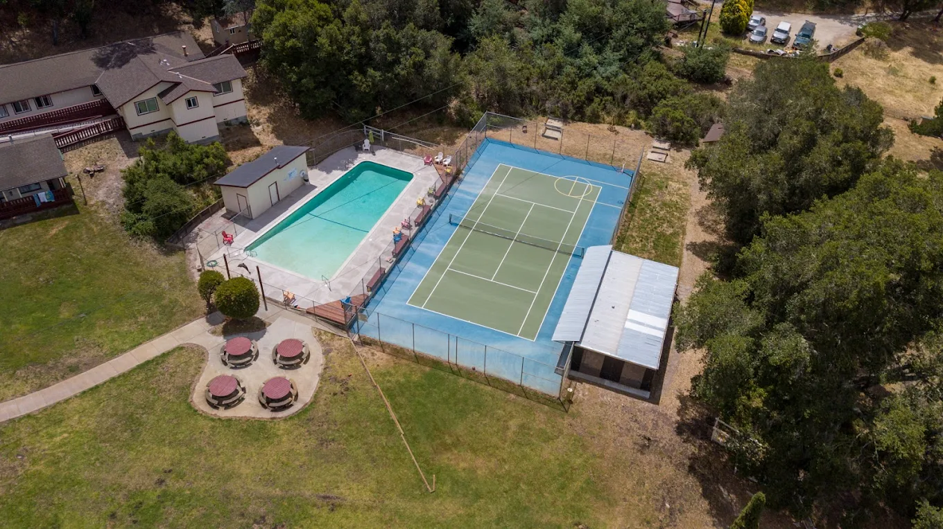 Aerial view of pool and tennis court on wooded grounds