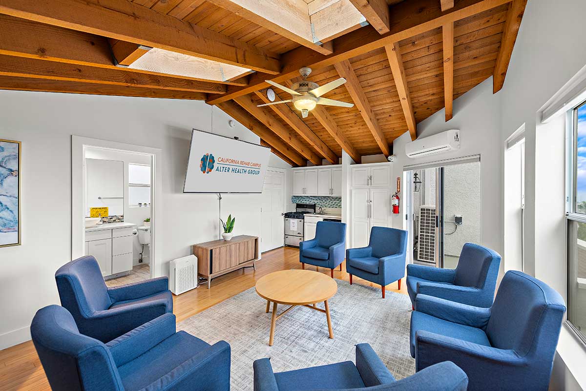 Bright group meeting area with blue armchairs arranged in a circle beneath a vaulted exposed-wood ceiling