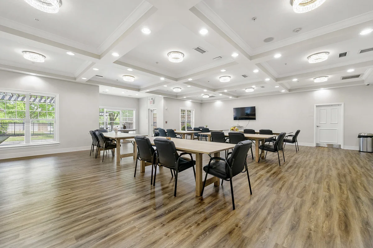 Large group therapy room with tables, comfortable seating, television, and natural light
