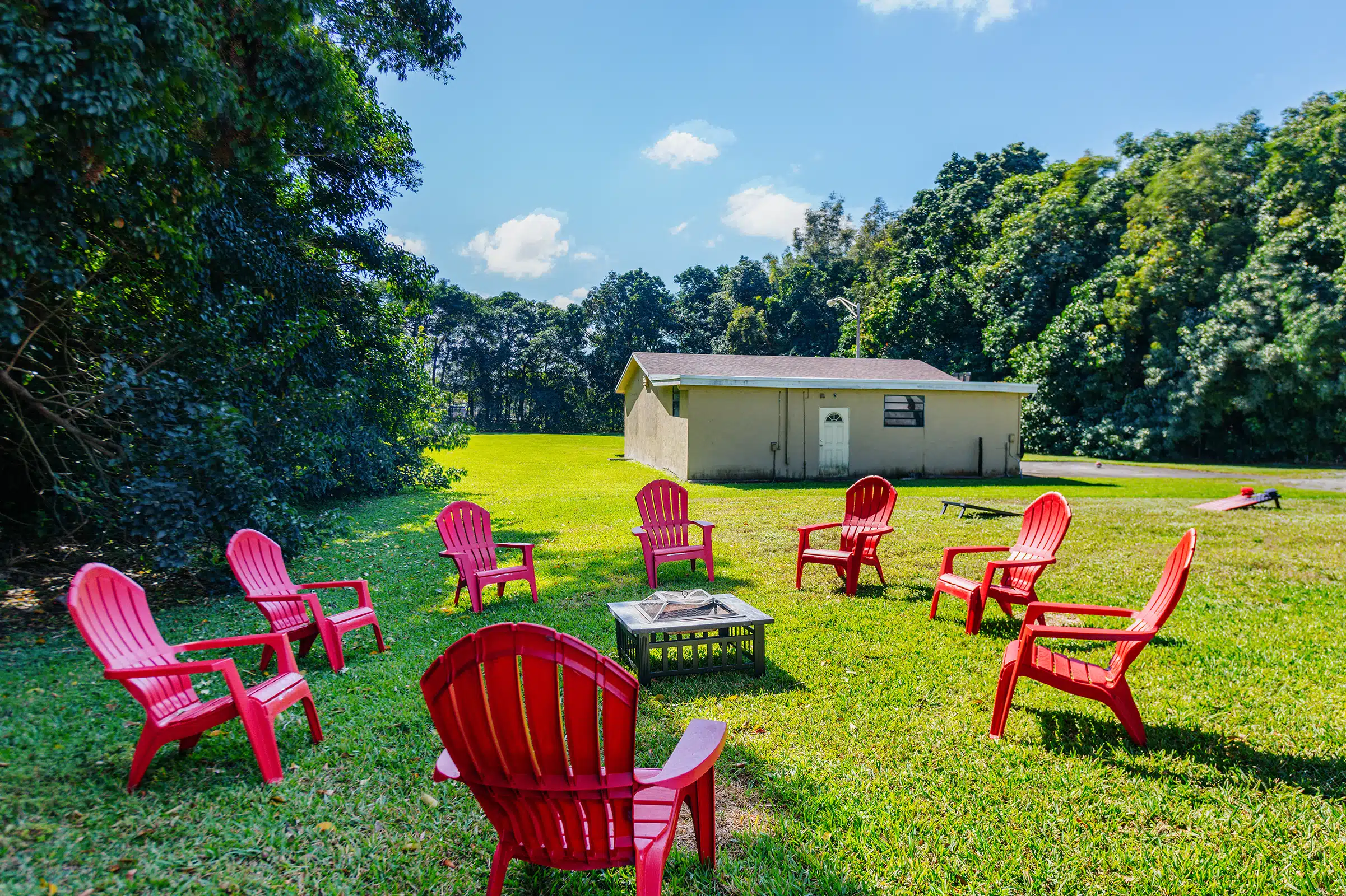 Red chairs in a circle around a firepit on grass
