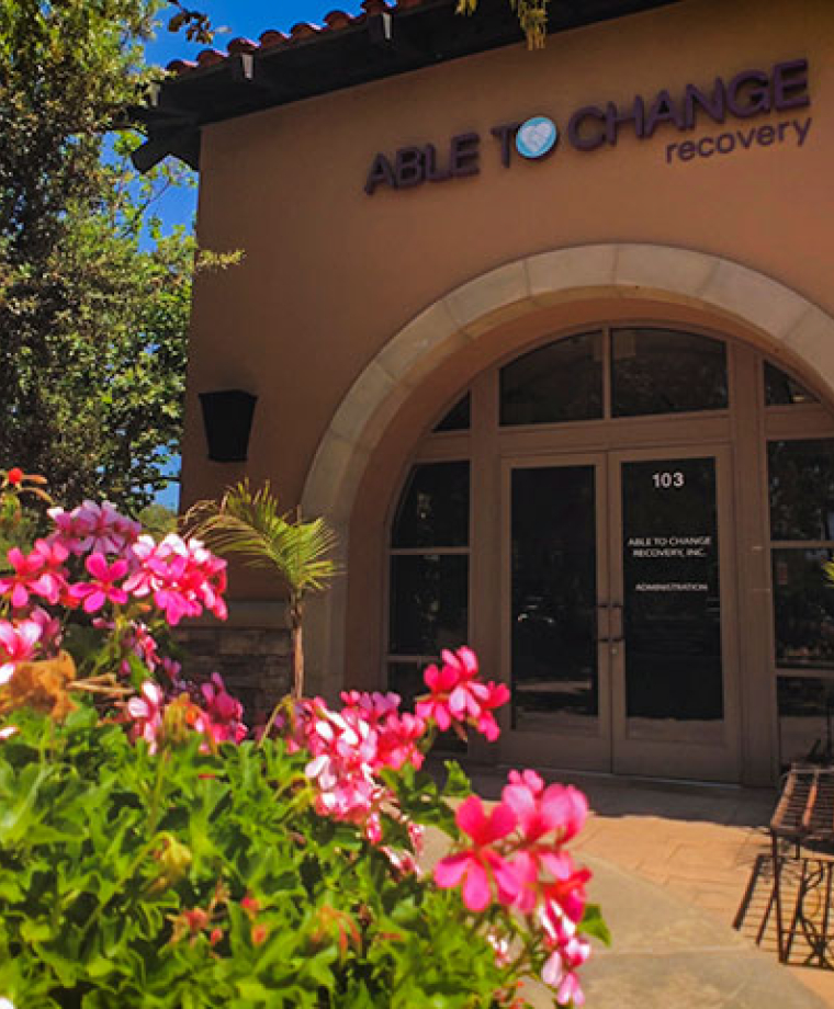 Rehab center entrance framed by bright pink flowers in garden