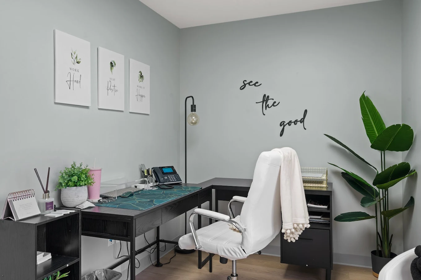 Minimalist office space with white chair, desk, and motivational wall decor