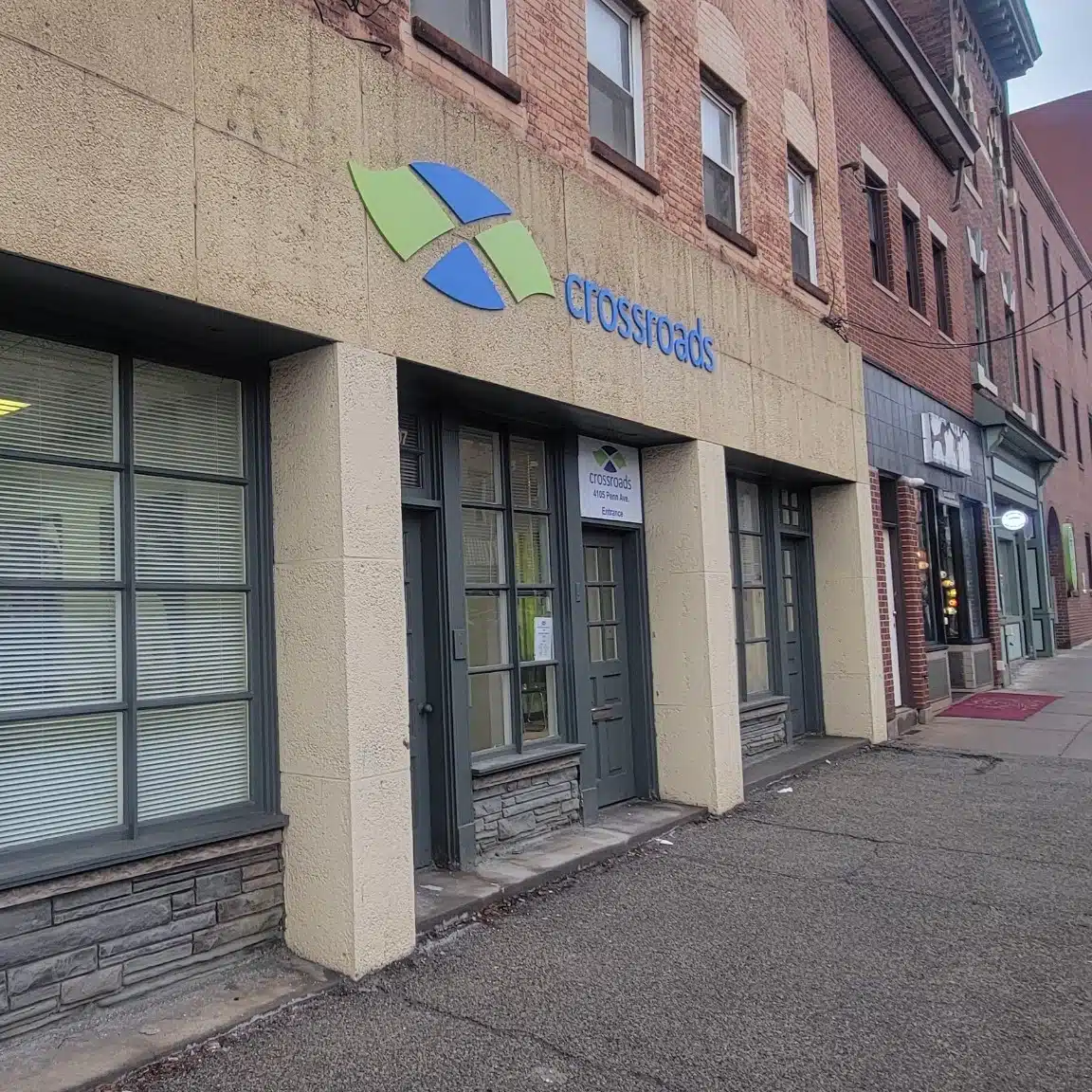 Crossroads storefront along city street with entrance door