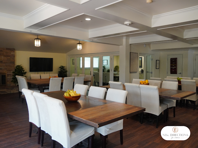 Bright dining room with long wooden tables and cushioned chairs