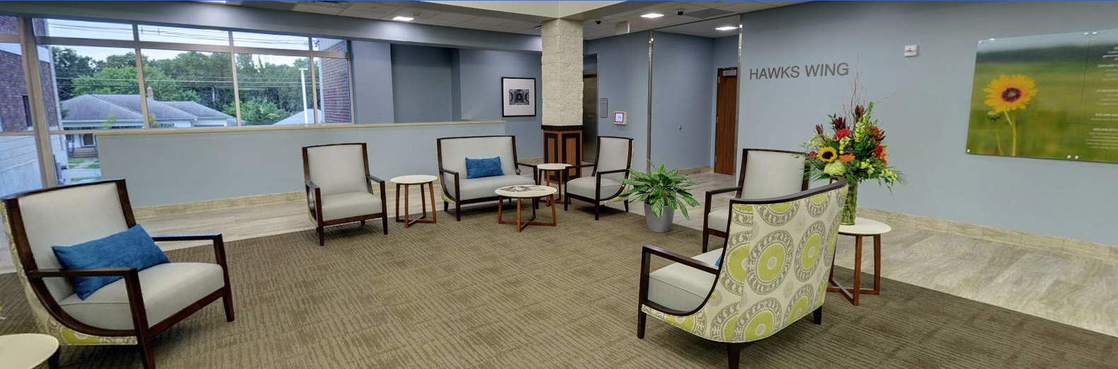 Seating area with modern chairs, flowers, and large windows