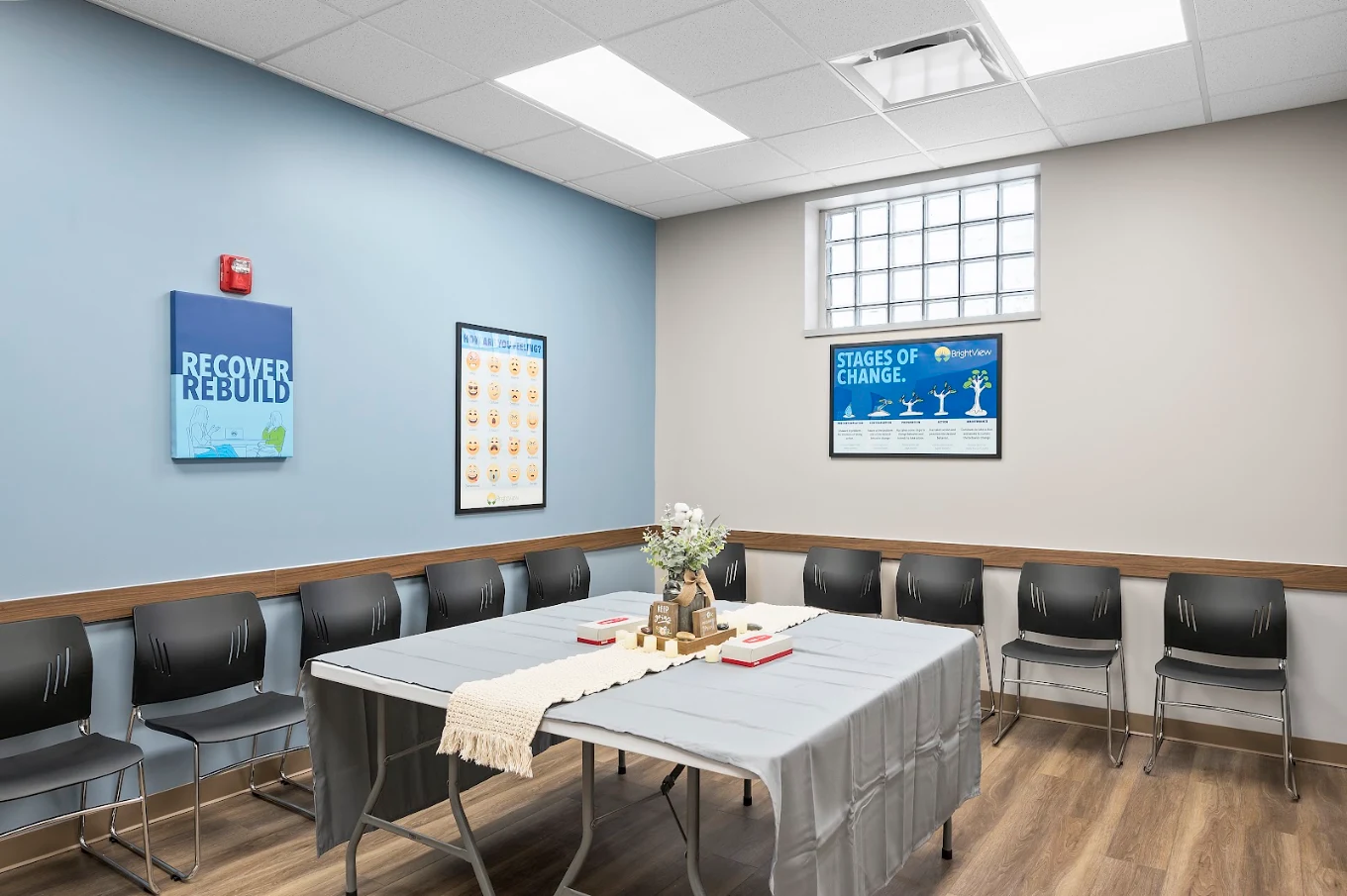 Group therapy room with table, chairs, and recovery posters