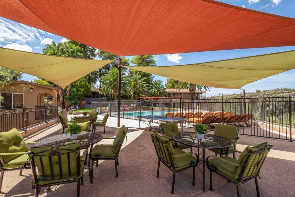 Outdoor seating area with tables and shade near pool