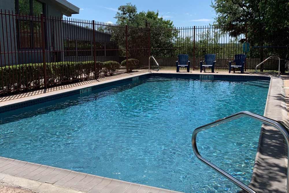 Rectangular pool with lounge chairs behind black fence