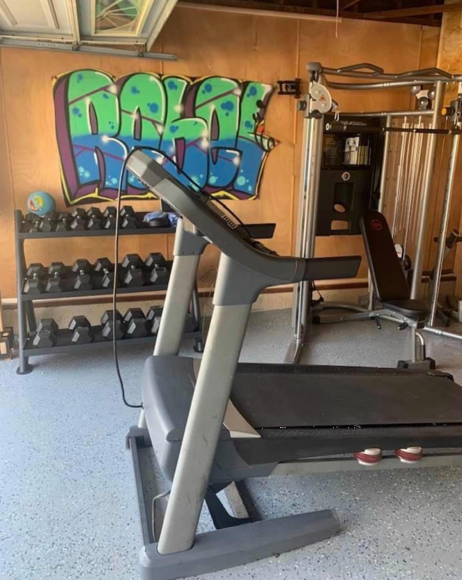 Gym with treadmill, weights, and bright wall art