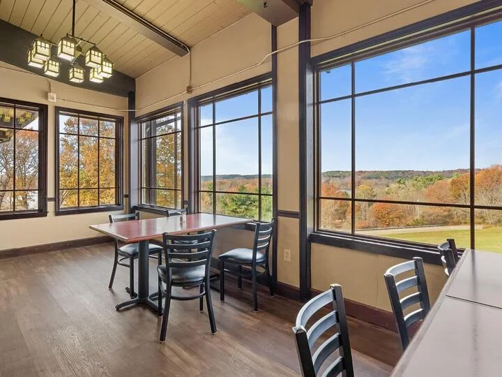 Dining tables beside large windows overlooking wooded hills